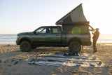 Ram Power Wagon with an overlanding camper on a beach at sunset. Ideal RV rental for ocean adventures.