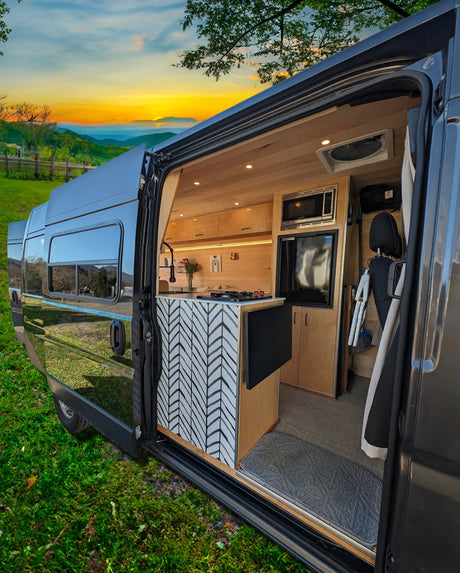 Experience RV rental luxury! This custom van features a modern kitchen, cozy interior, and scenic mountain views at sunset.