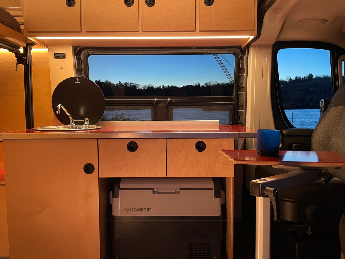 Spacious RV rental interior featuring a modern wood-paneled kitchen with sink, Dometic fridge, and scenic window views. — photo 8