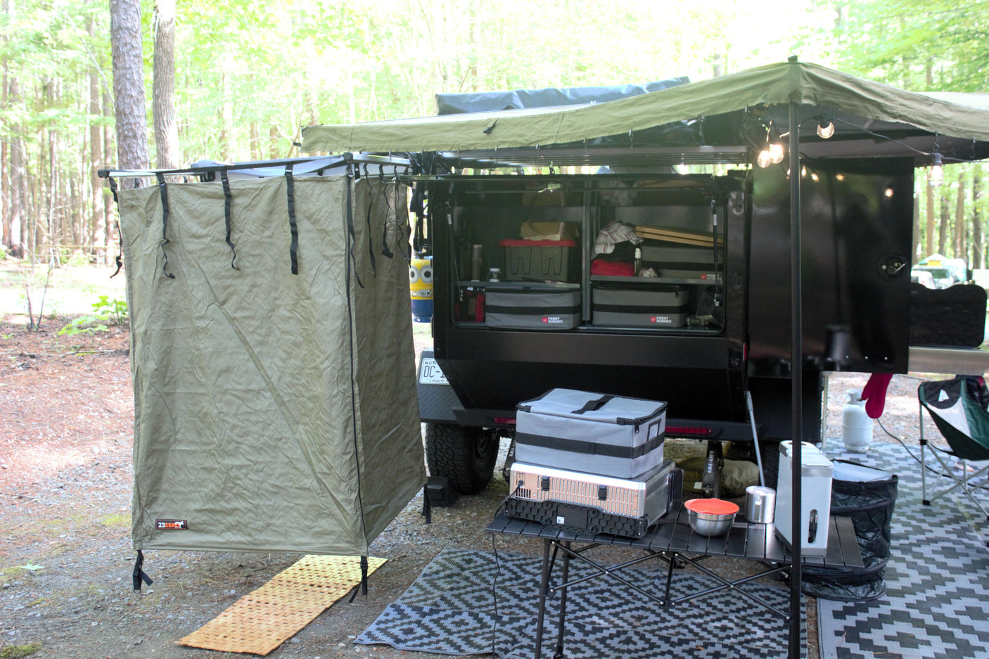Campsite ready! This overlanding trailer, with an awning, shower tent, and camp gear, is ideal for an RV rental.