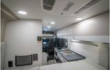 Modern rv rental interior with a compact kitchen, overhead storage, and a comfy bed, leading to the driver's cabin.