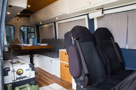 Cozy rv rental interior: dining table, bench, seats, and storage for a comfortable campervan adventure.