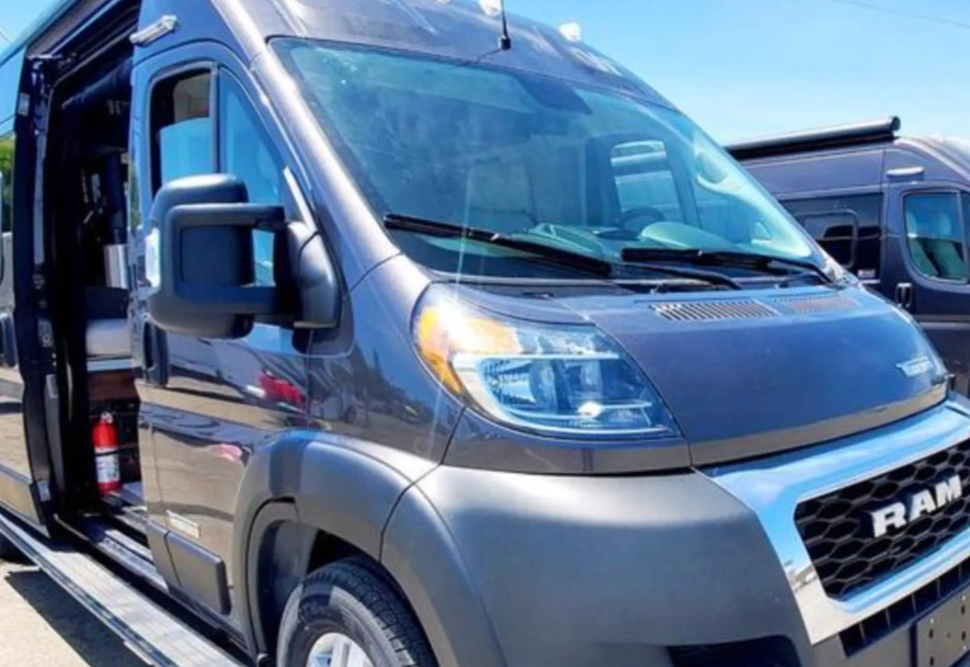  side door open to interior with fire extinguisher. Another van visible behind.|Man smiles by his dark gray Winnebago rv rental van — photo 2
