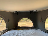 Cozy RV rental interior with a comfortable bed, large arched window, and mesh screens showing an outdoor view.