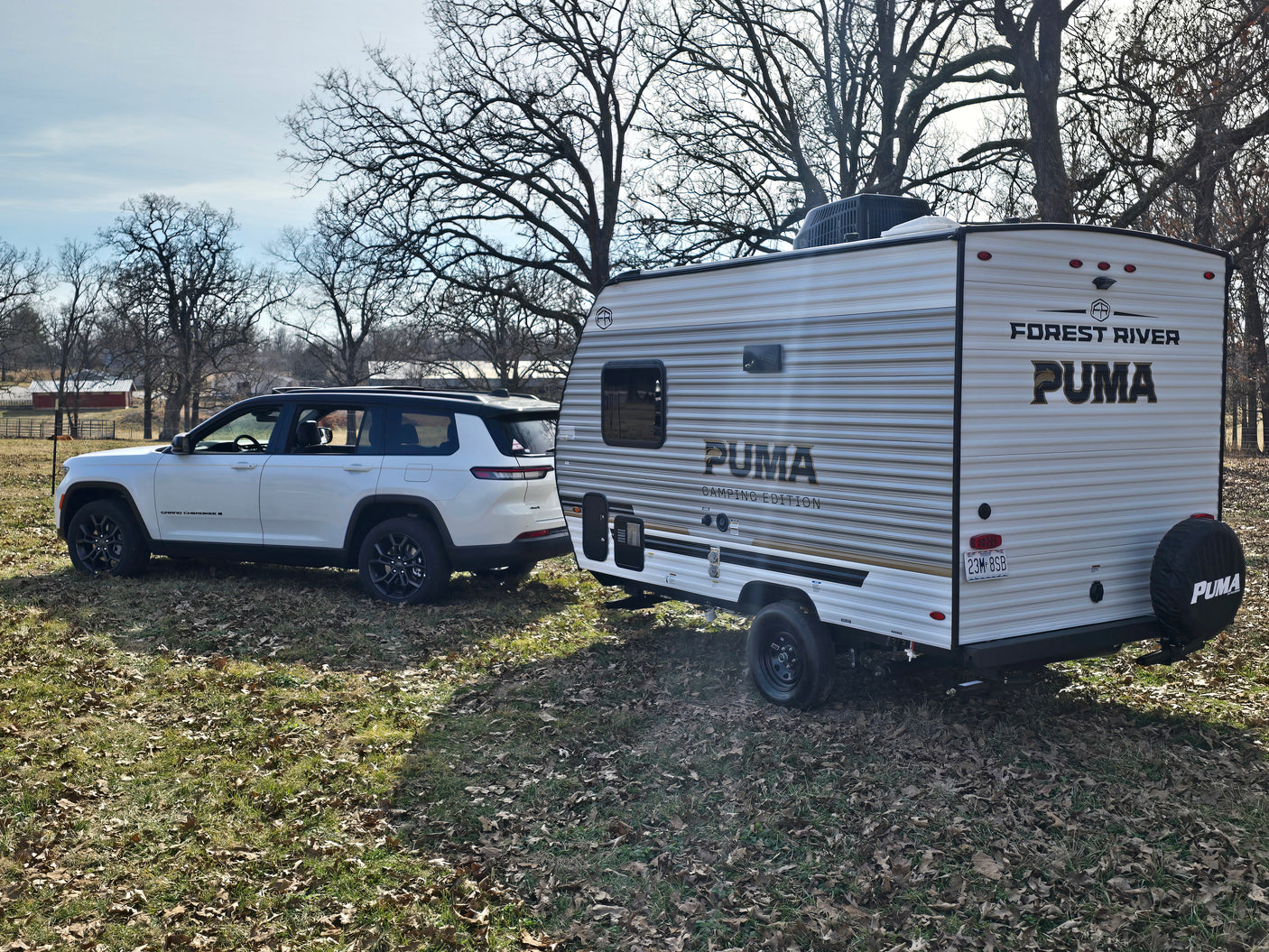 White Jeep Grand Cherokee L towing a Forest River Puma travel trailer. Ideal for your next RV rental adventure.