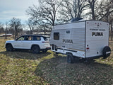 White Jeep Grand Cherokee L towing a Forest River Puma travel trailer. Ideal for your next RV rental adventure.