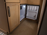 Open mini-fridge inside an RV rental with light wooden cabinetry and textured flooring, perfect for your next trip.