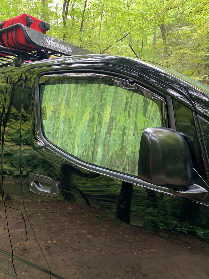 Adventure awaits! This black rv rental, with a Yakima roof rack, is parked in a lush forest. Side window covered for privacy. — photo 5