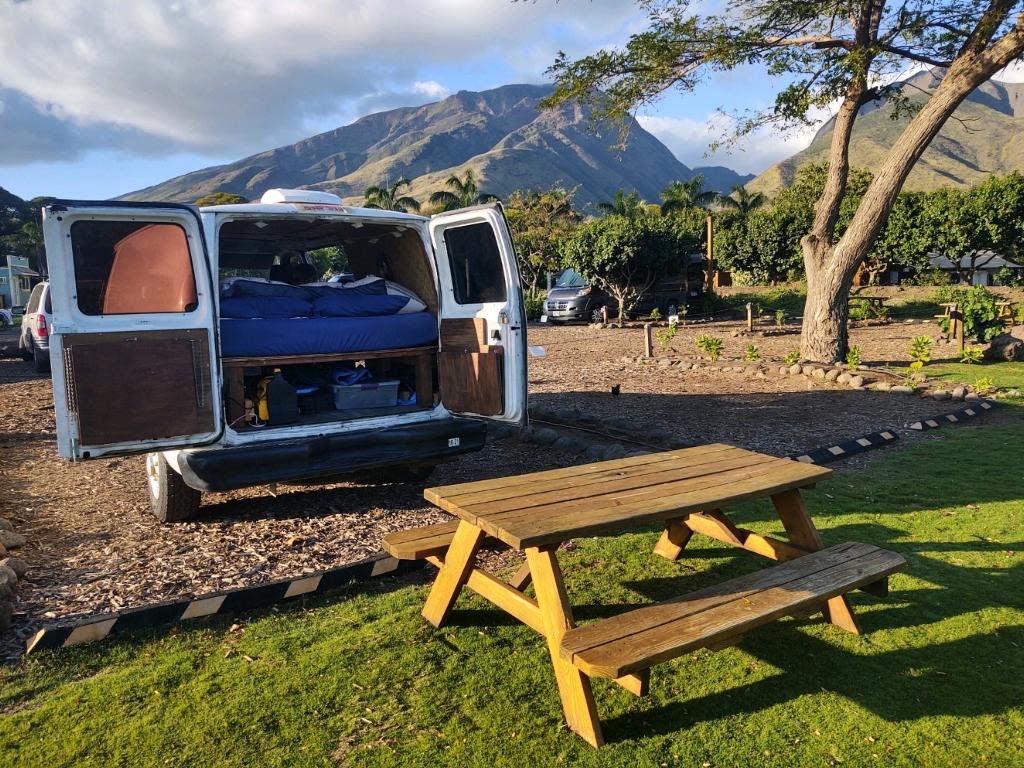  showcasing golden skies & peaceful waters.|RV rental interior: A converted camper van's cozy living space with a bed — photo 5