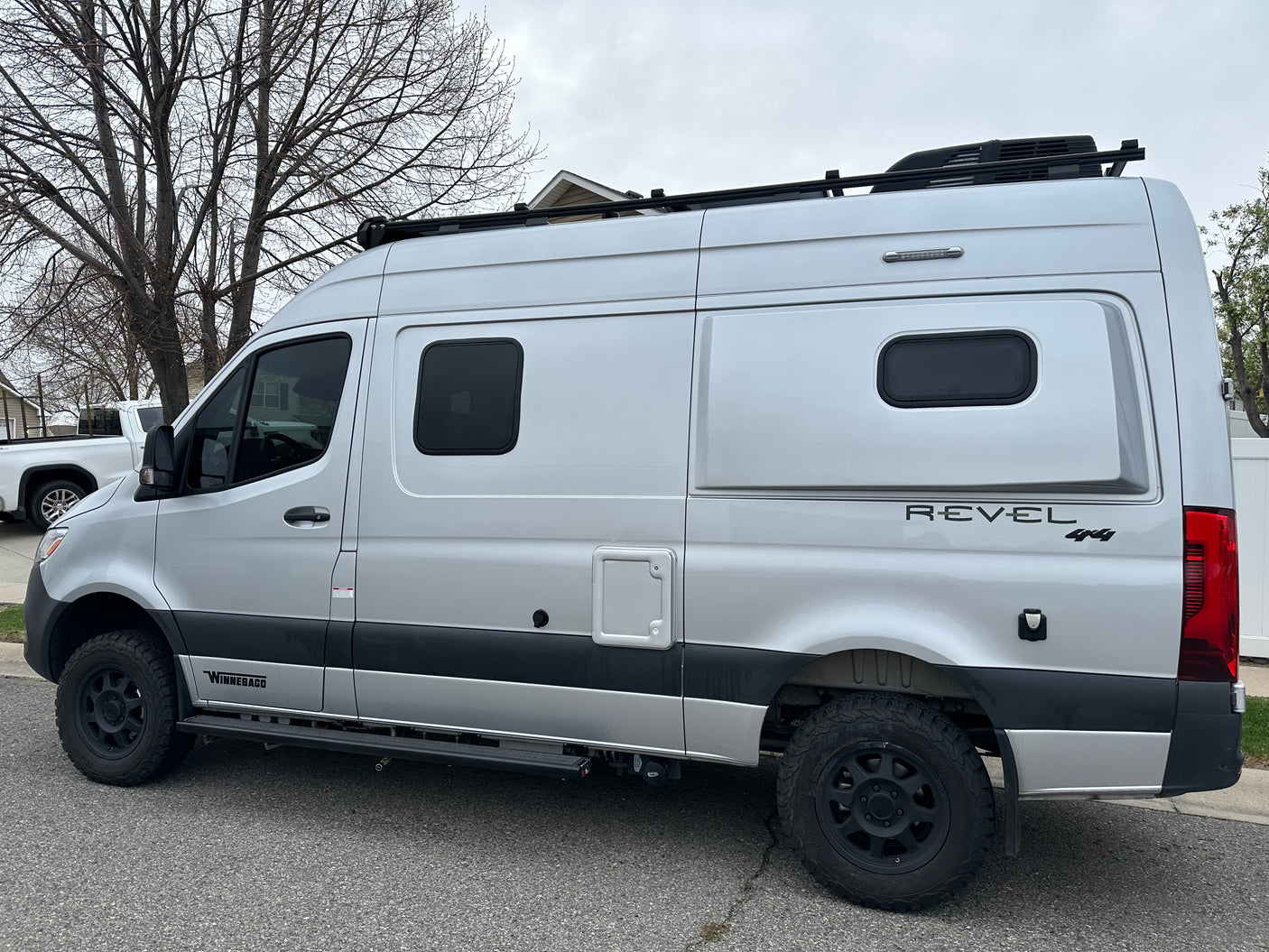 Silver Winnebago Revel 4x4 camper van, ideal for rv rental, featuring off-road tires and a roof rack.