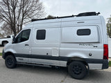 Silver Winnebago Revel 4x4 camper van, ideal for rv rental, featuring off-road tires and a roof rack.