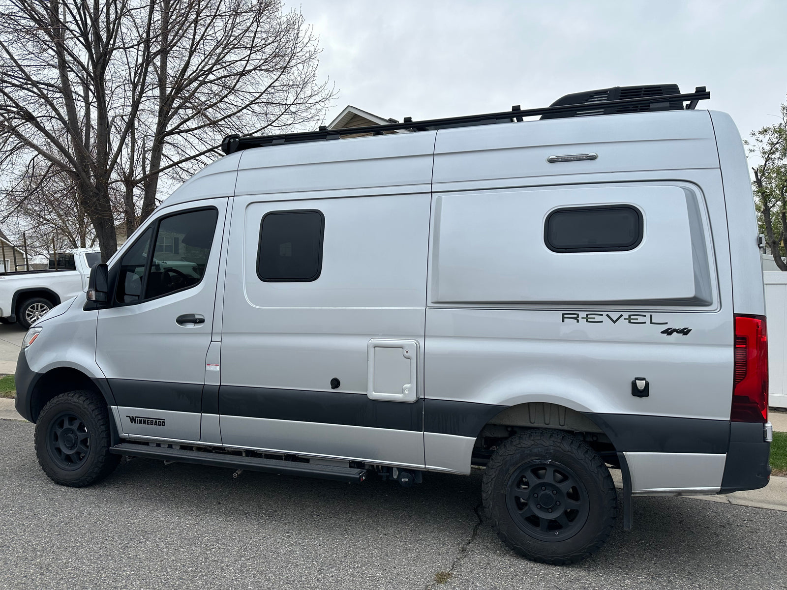 Silver Winnebago Revel 4x4 camper van, ideal for rv rental, featuring off-road tires and a roof rack.