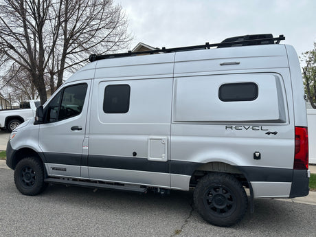 Silver Winnebago Revel 4x4 camper van, ideal for rv rental, featuring off-road tires and a roof rack.