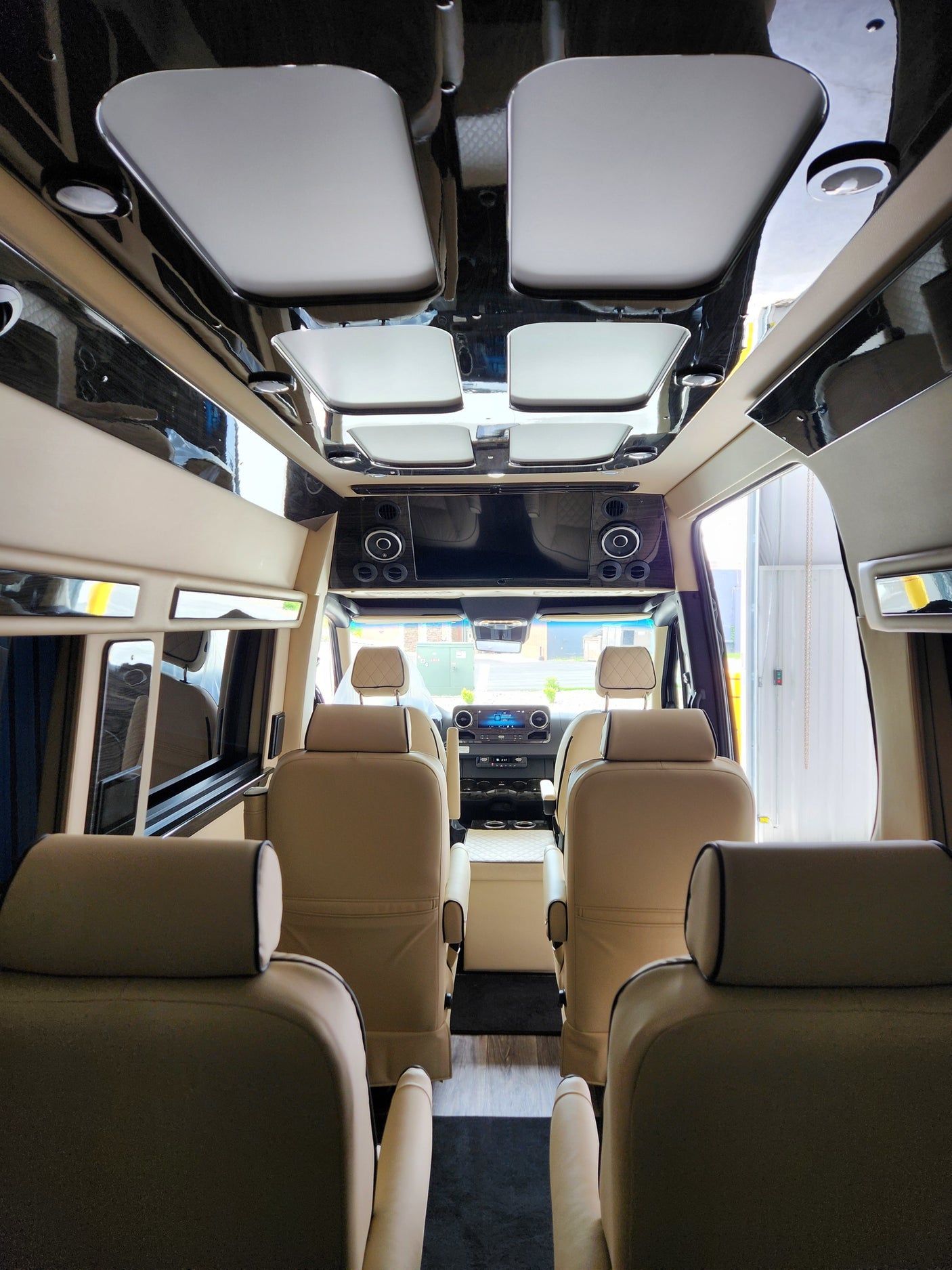 Spacious RV rental vehicle interior, featuring luxurious tan seats, a glossy ceiling, and an entertainment system.