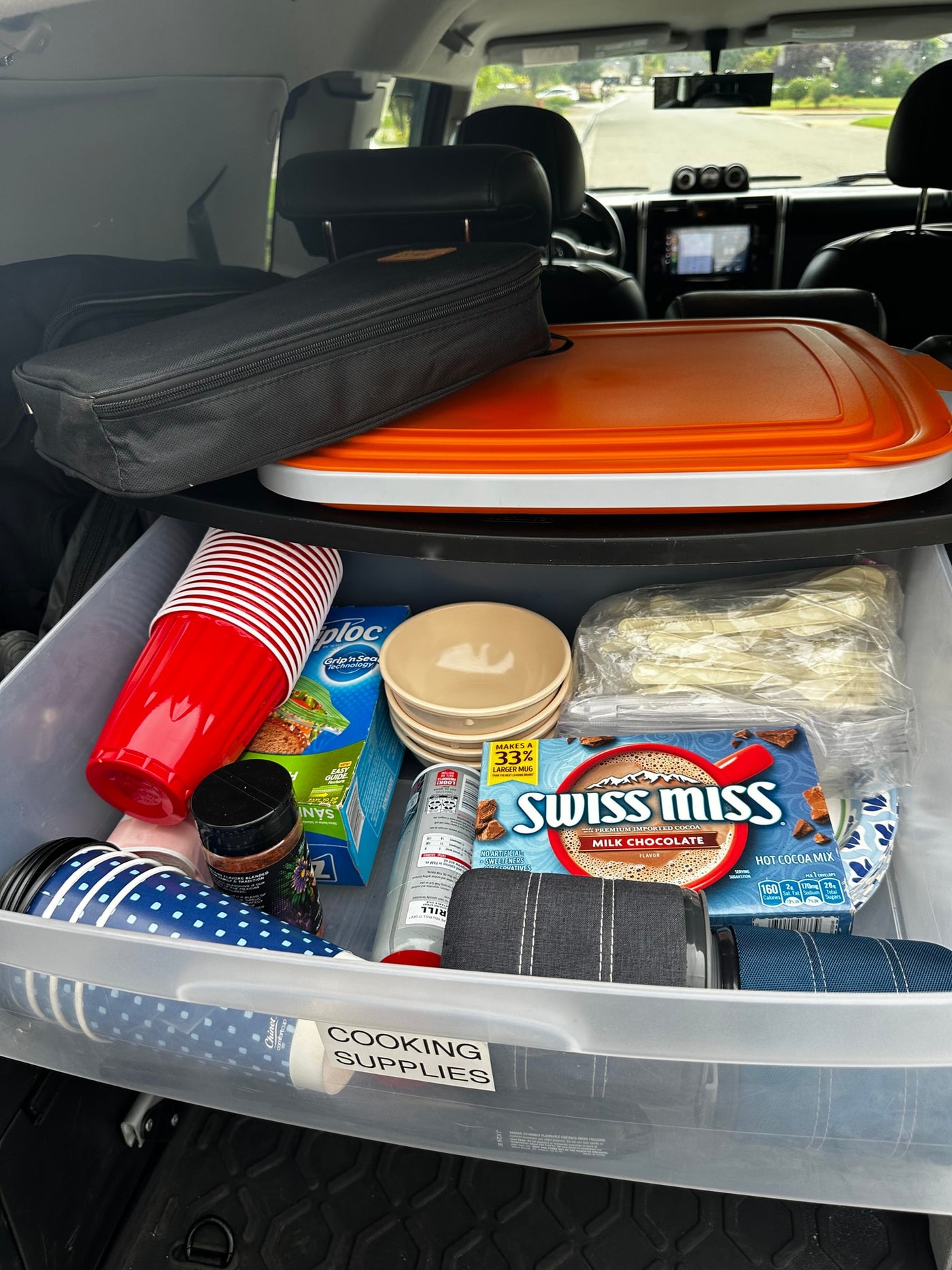 RV rental ready: An organized bin of cooking supplies with cups, hot cocoa, bowls, and cutlery, packed for a camping trip. — photo 16
