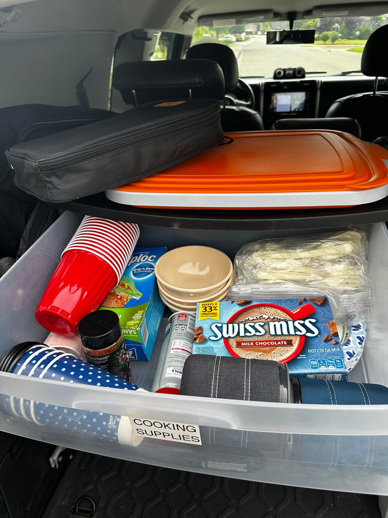 RV rental ready: An organized bin of cooking supplies with cups, hot cocoa, bowls, and cutlery, packed for a camping trip. — photo 16
