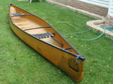 Yellow canoe with black trim and "Souris River Canoes" logo on green grass. Ideal for an RV rental outdoor trip.