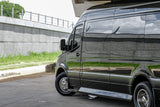 Sleek black Mercedes Sprinter van, often used for RV rental or luxury transport, parked next to a concrete wall.