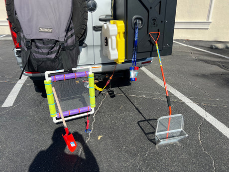 RV rental equipped with outdoor gear: TRASHAROO bag, jerry cans, and various sifting tools for beach adventures.