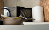 RV rental: Compact storage with paper towels, a mesh net, and stacked dishes with cleaning supplies.