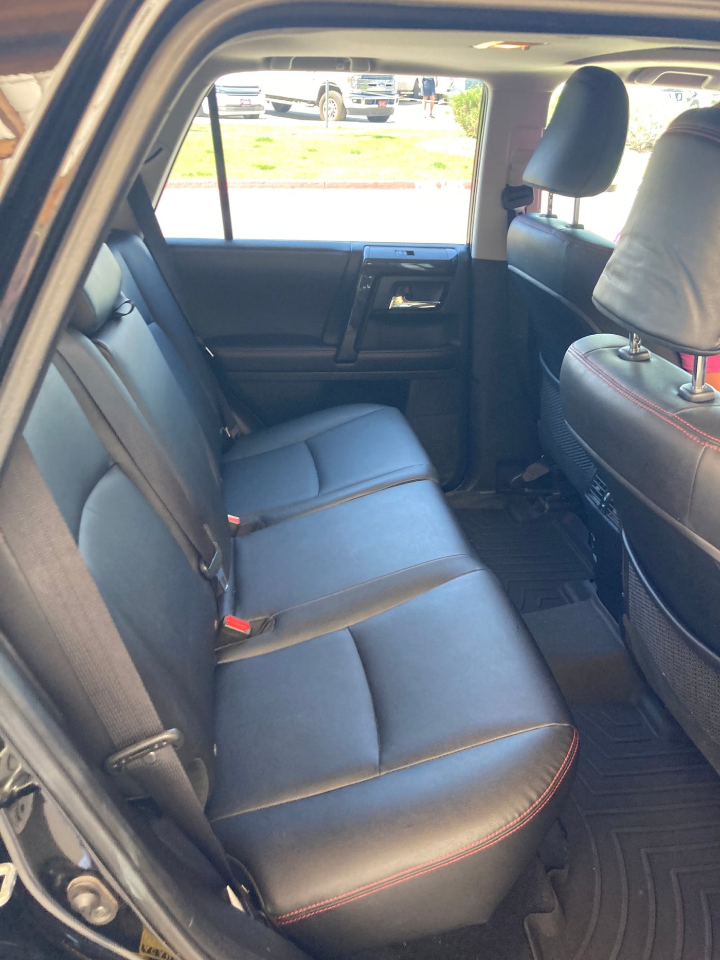 Black leather rear seats with red stitching and floor mats in an SUV, ready for travel or an rv rental adventure. — photo 11