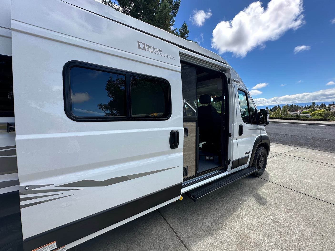 White National Park Foundation RV rental camper van with its side door open and step extended.