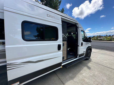 White National Park Foundation RV rental camper van with its side door open and step extended.