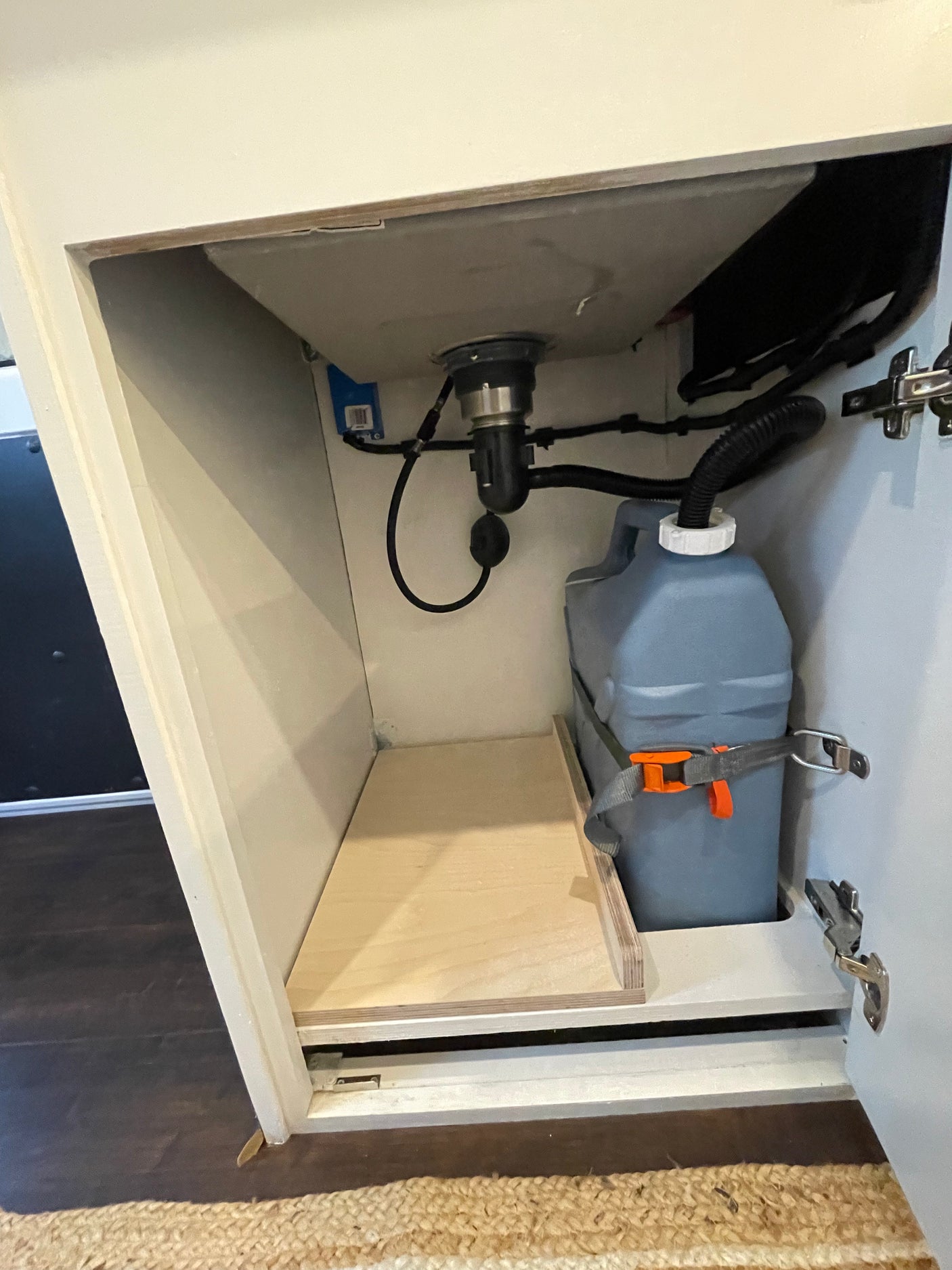 RV rental under-sink cabinet: Shows grey water tank, sink drain, and plumbing for a compact water system.