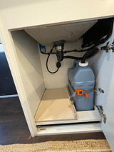 RV rental under-sink cabinet: Shows grey water tank, sink drain, and plumbing for a compact water system.