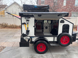 A white and black compact camper trailer with a rooftop tent and outdoor kitchen setup, perfect for your next rv rental adventure.