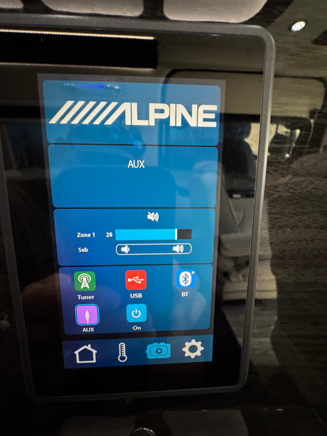 Digital Alpine infotainment system in an RV rental, showing audio input options (AUX, USB, BT) and volume controls.