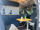 Stylish rv rental van interior featuring a hexagon-tiled kitchen, comfy seating, and dining setup.