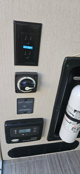 RV rental control panel: GFCI outlet, battery switch, inverter remote, solar charger, and fire extinguisher.