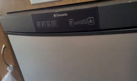 Dometic RV rental fridge control panel, showing power, gas, battery, temp settings, and warning symbols clearly.