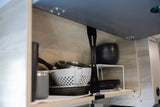 RV rental kitchen: organized cabinet with pans, colander, plates, and cups for efficient compact storage.