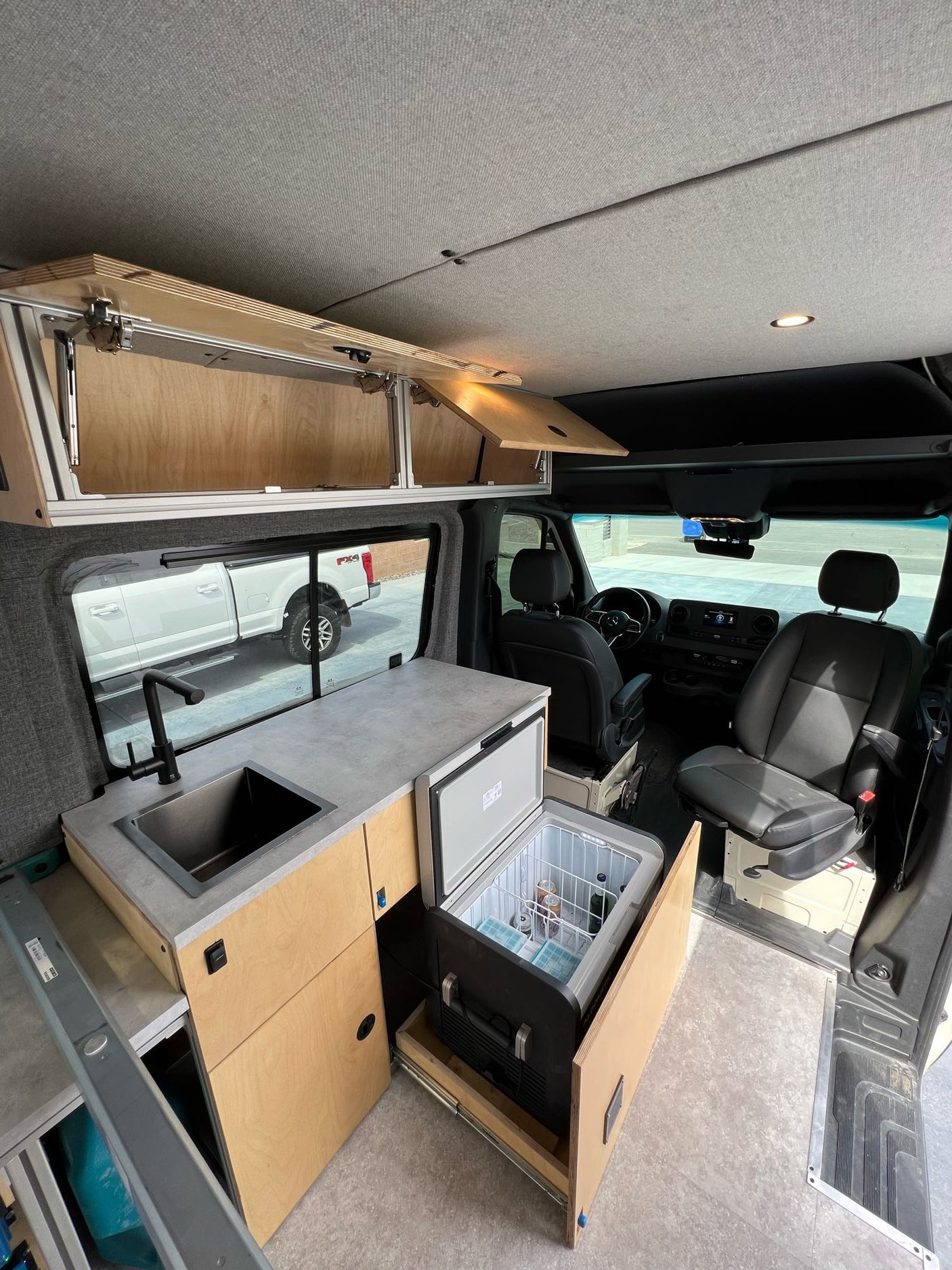 Spacious RV rental interior featuring a modern kitchenette with sink, pull-out fridge, and ample storage for comfortable adventures.