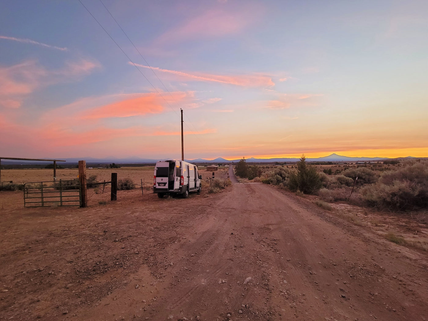  mountains under cloudy sky.|Stunning sunset paints the sky over an RV rental van on a dusty desert road — photo 3