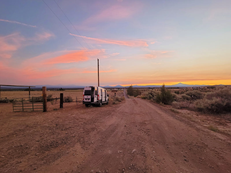  mountains under cloudy sky.|Stunning sunset paints the sky over an RV rental van on a dusty desert road — photo 3