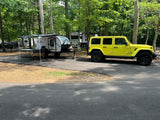 Yellow Jeep & FREESOLO teardrop RV/trailer at a wooded campsite, showcasing a great option for an rv rental adventure.