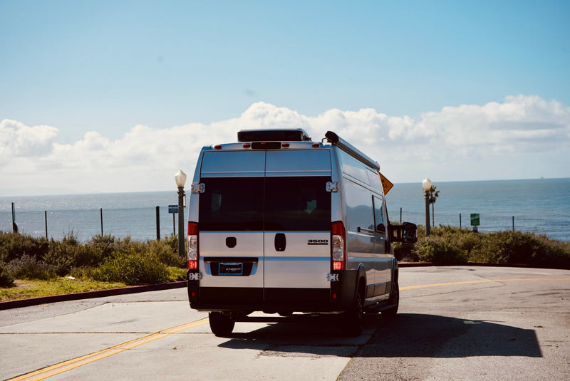  and cozy dining.|A silver RV rental camper van is parked on a coastal road with the ocean in the background — photo 5