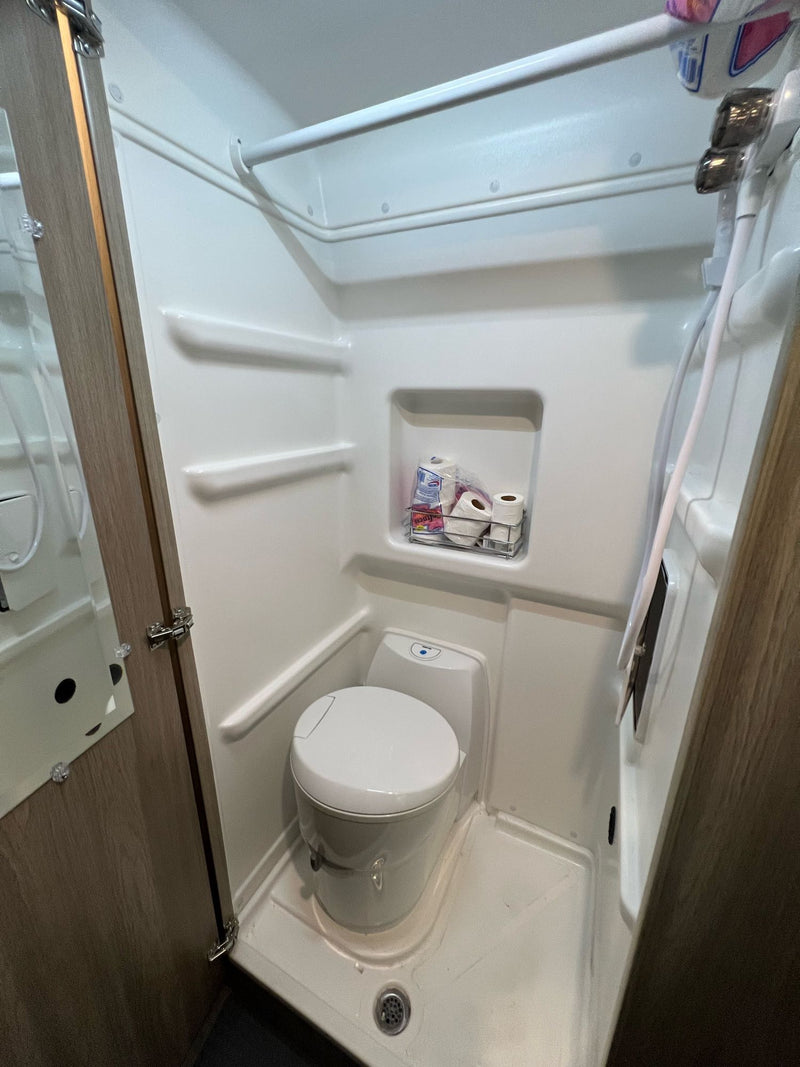  embracing van life.|White RV rental van parked at night in a marina lot (spot 355).|Happy woman and her fluffy dog smile inside a modern RV rental. A comfortable setup for pet-friendly road trip adventures.|RV rental interior: cozy plaid bed — photo 8
