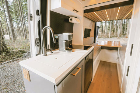 Spacious RV rental interior: modern kitchen, cozy dining, and bed area. Perfect for nature escapes from the open door!