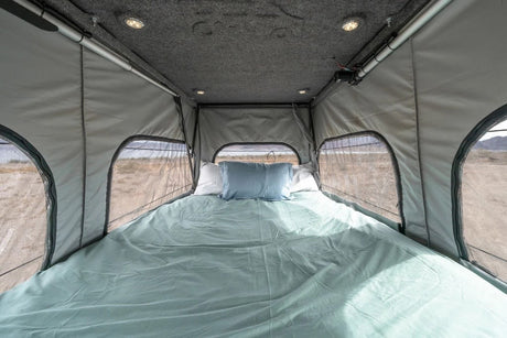 Enjoy comfortable nights in this pop-top camper interior, ideal for an RV rental adventure. Features a cozy bed and scenic views.