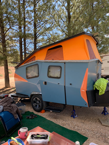 A Taxa Cricket pop-up rv rental at a pine forest campsite, offering a comfortable outdoor escape.