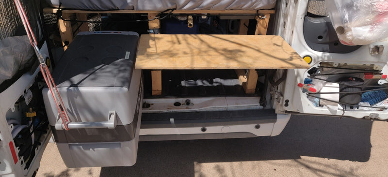 Rear view inside an RV rental van showing a Dometic cooler, wooden kitchen area with water tanks, and organized storage. — photo 6