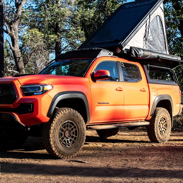  parked amidst tall pines for camping.|Orange Toyota Tacoma — photo 6