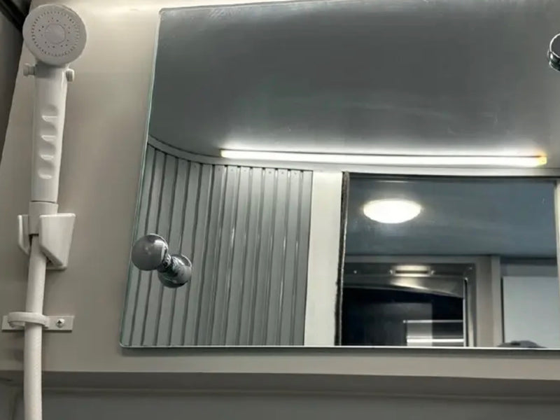  offering a view out the back windows to trees and a pedestrian crossing sign.|RV rental: compact bathroom interior features a toilet — photo 4