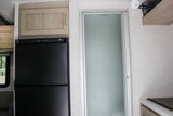 This rv rental interior features a black refrigerator, light wood cabinets, and a frosted glass shower door, ideal for mobile living.