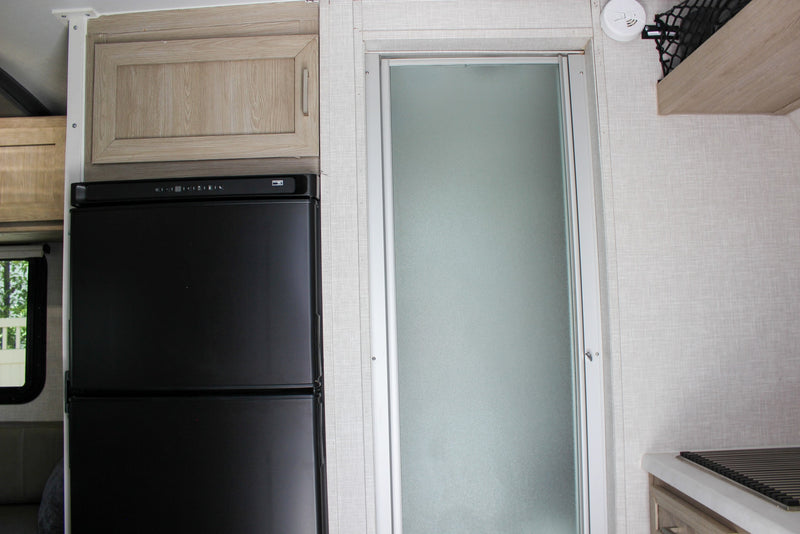 and a glass vase with green plant stems.|An RV rental kitchen features a compact stove with a frying pan — photo 37