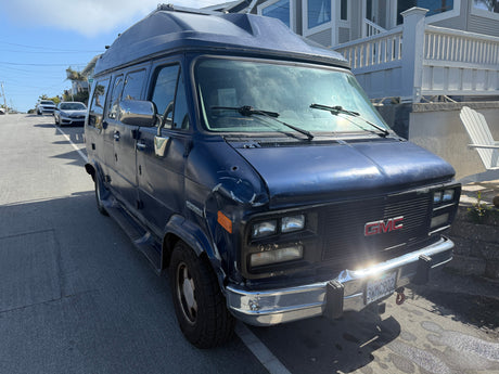 This blue GMC Vandura camper van, with its distinctive high roof, is ready for your next RV rental road trip adventure.